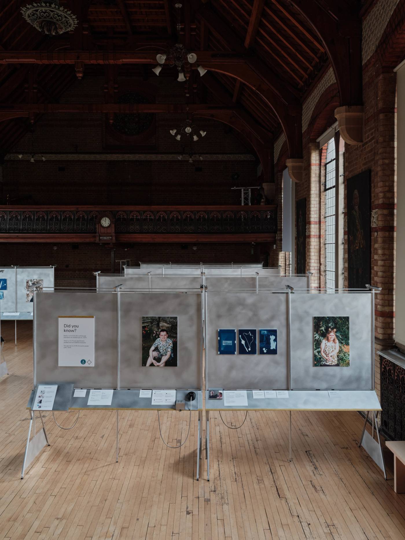 A photograph of a cluster of exhibition showcases made of aluminium panelling set within grand hall with ornate timber ceiling 