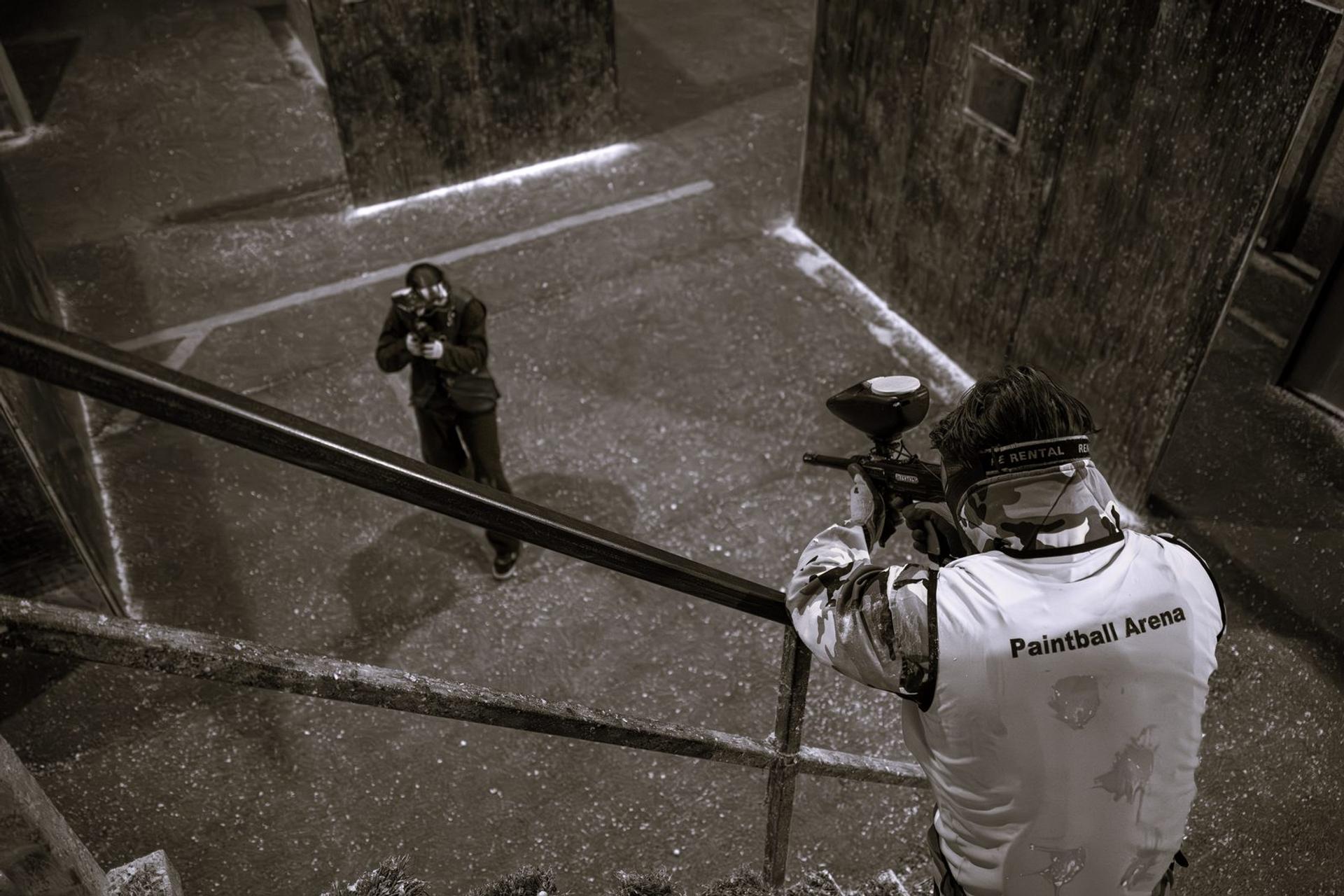Un joueur vise depuis un escalier un adversaire en bas dans la salle