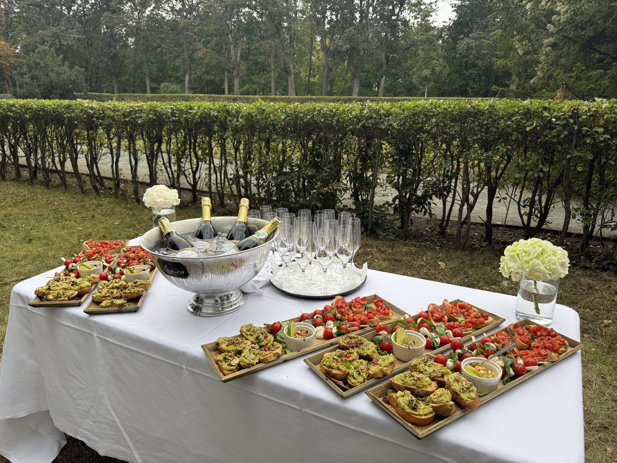 Catering-Buffet im Freien mit Bruschetta, Caprese-Spießen, Sekt im Kühler und Gläsern