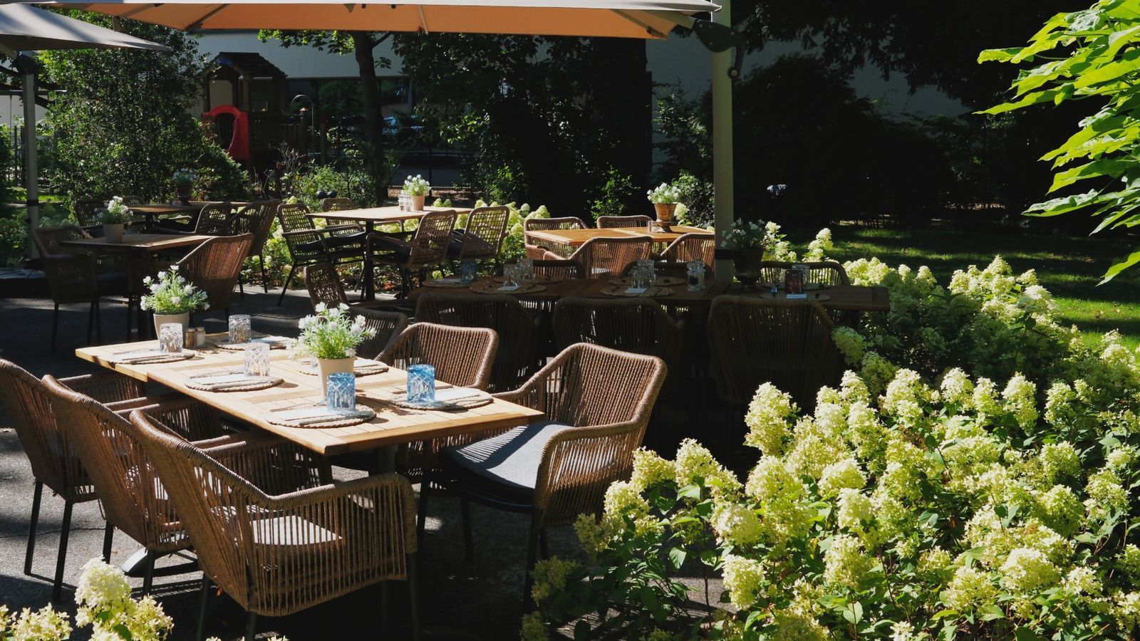 Gartenterrasse des TOMASA Potsdam mit Sonnenschirmen und Hortensien