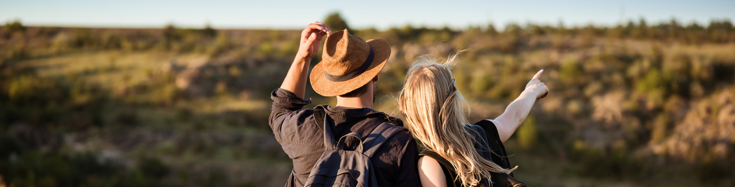 Casal de viajantes apontando para o horizonte