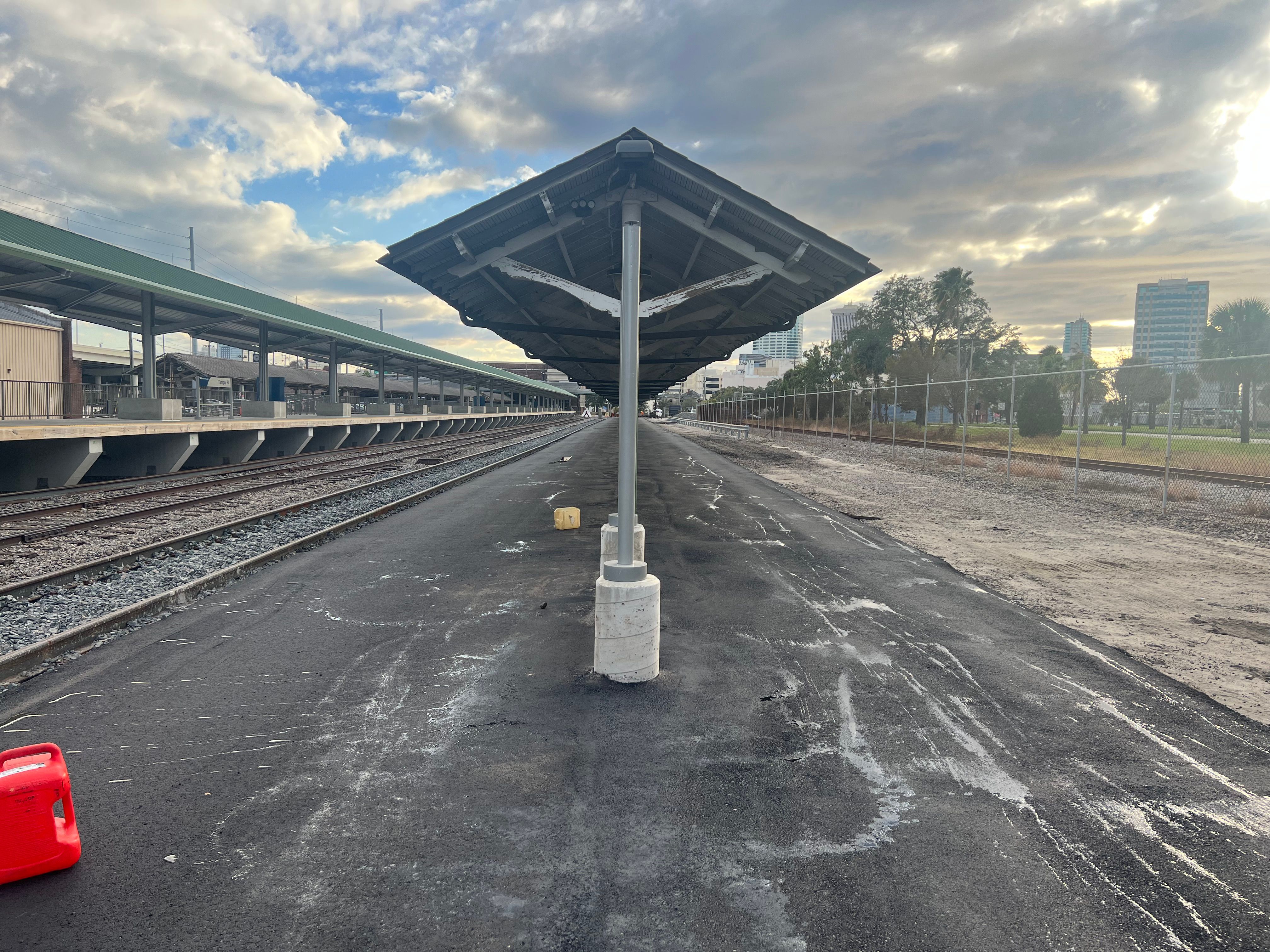 Compaction work on newly placed asphalt beside a covered platform