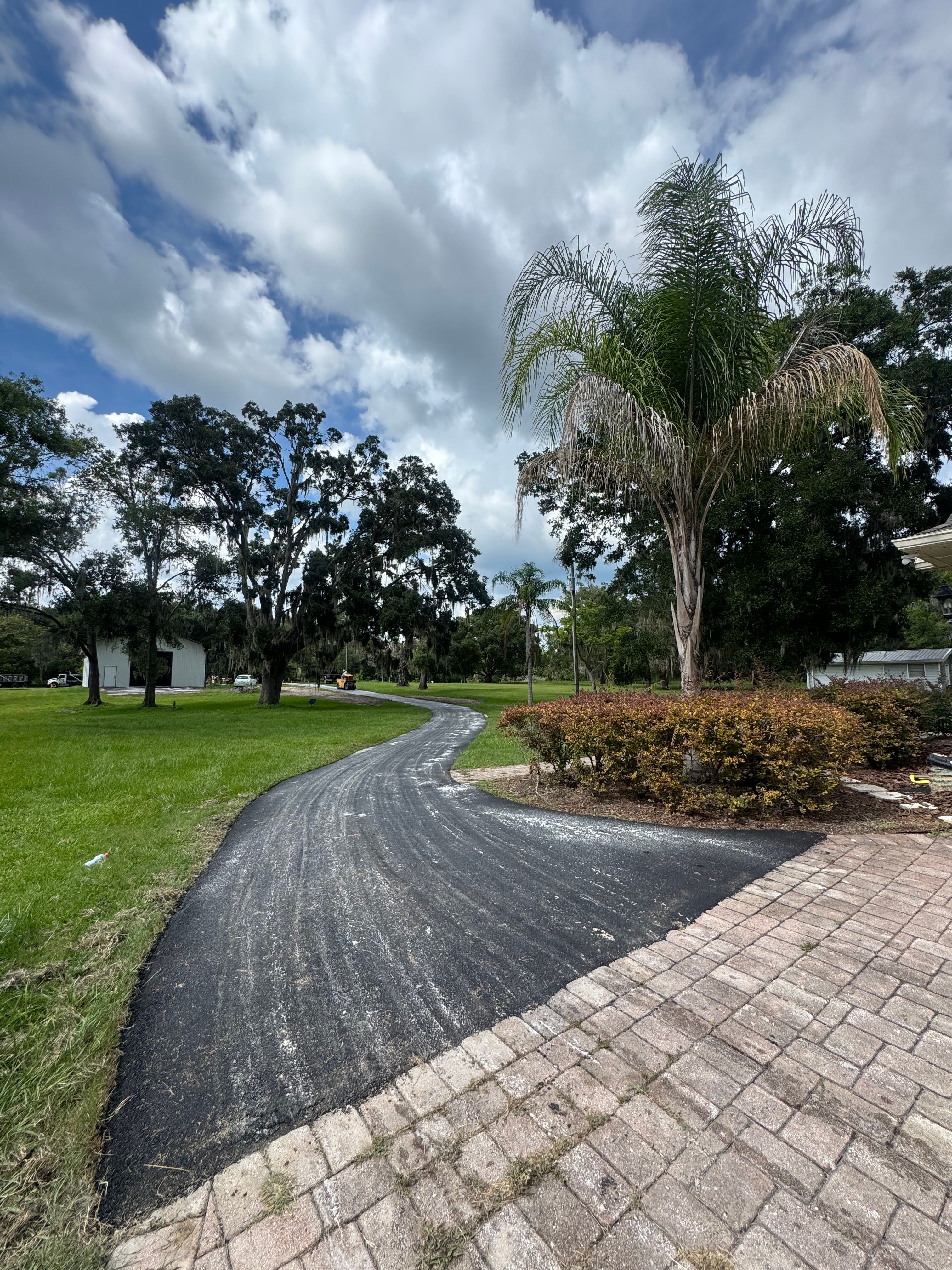 Completed asphalt driveway meeting an existing paver surface