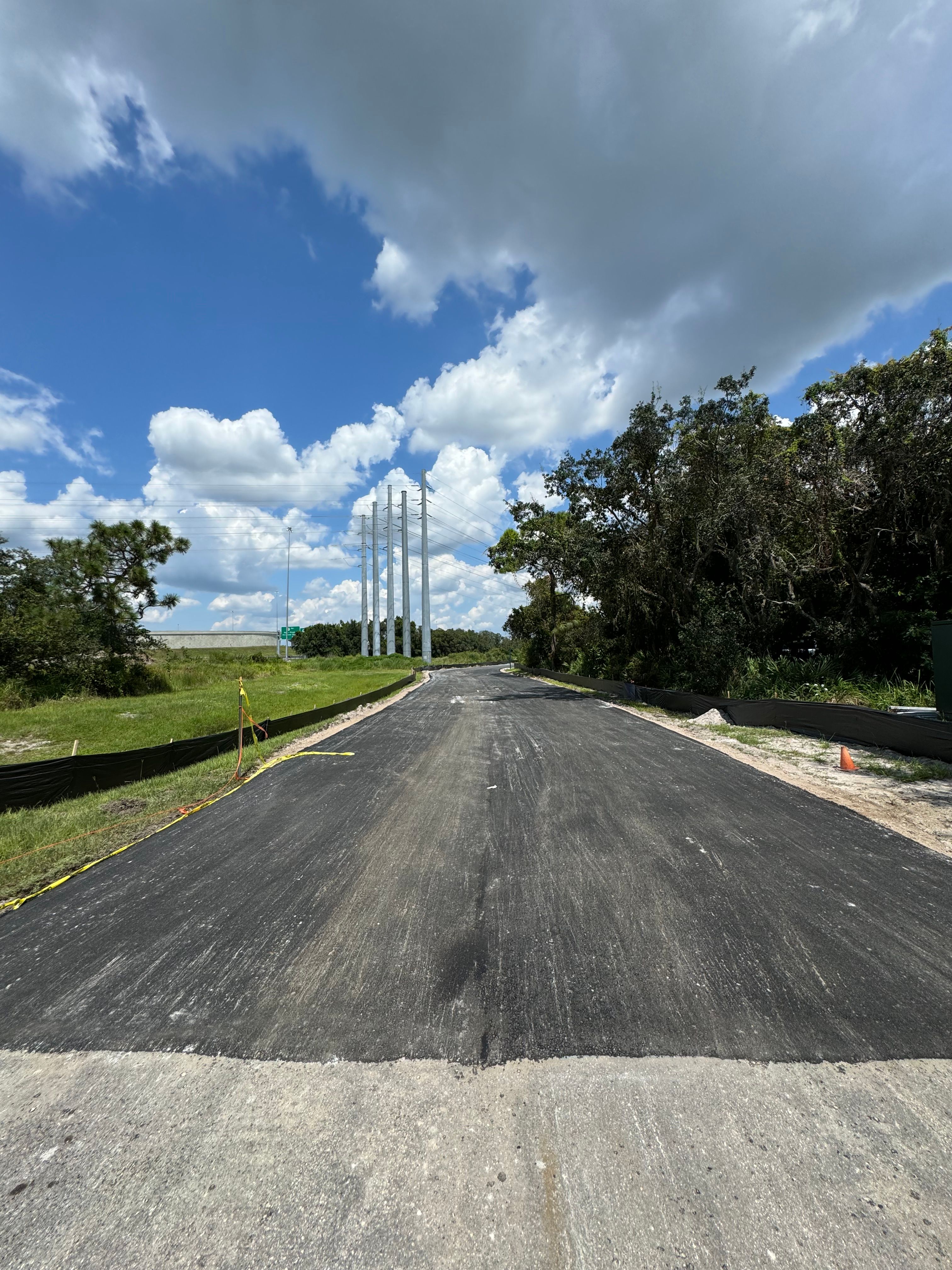 Completed asphalt road bordered by grass and trees