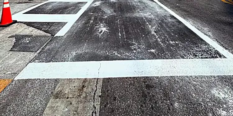 Repaired asphalt roadway with restored white crosswalk markings