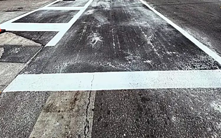 Repaired asphalt roadway with restored white crosswalk markings