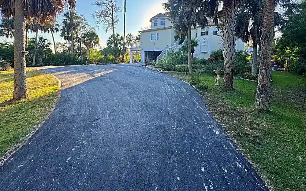 Finished residential asphalt millings driveway extension through tropical landscaping