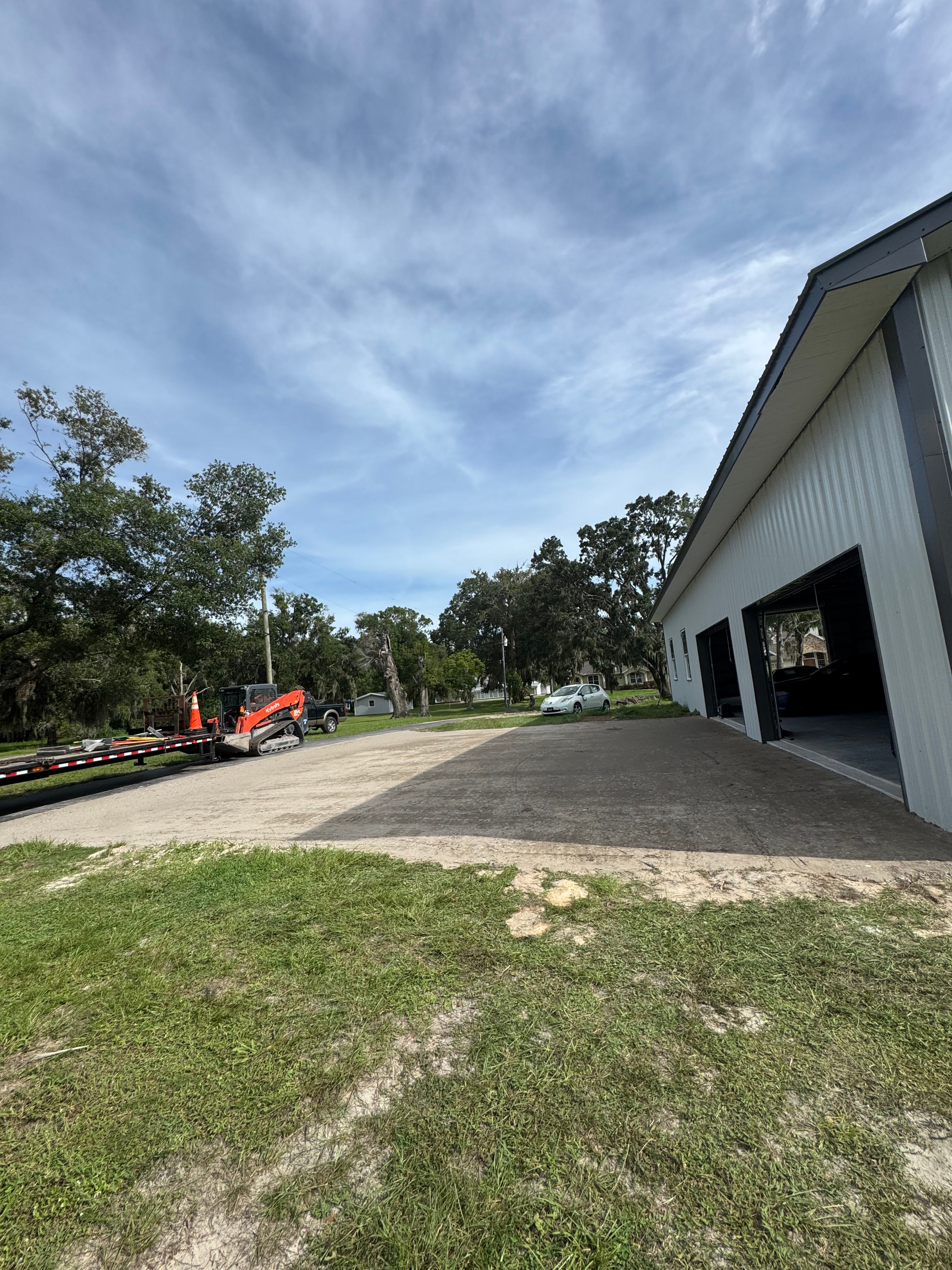 Asphalt installation in progress beside a large outbuilding