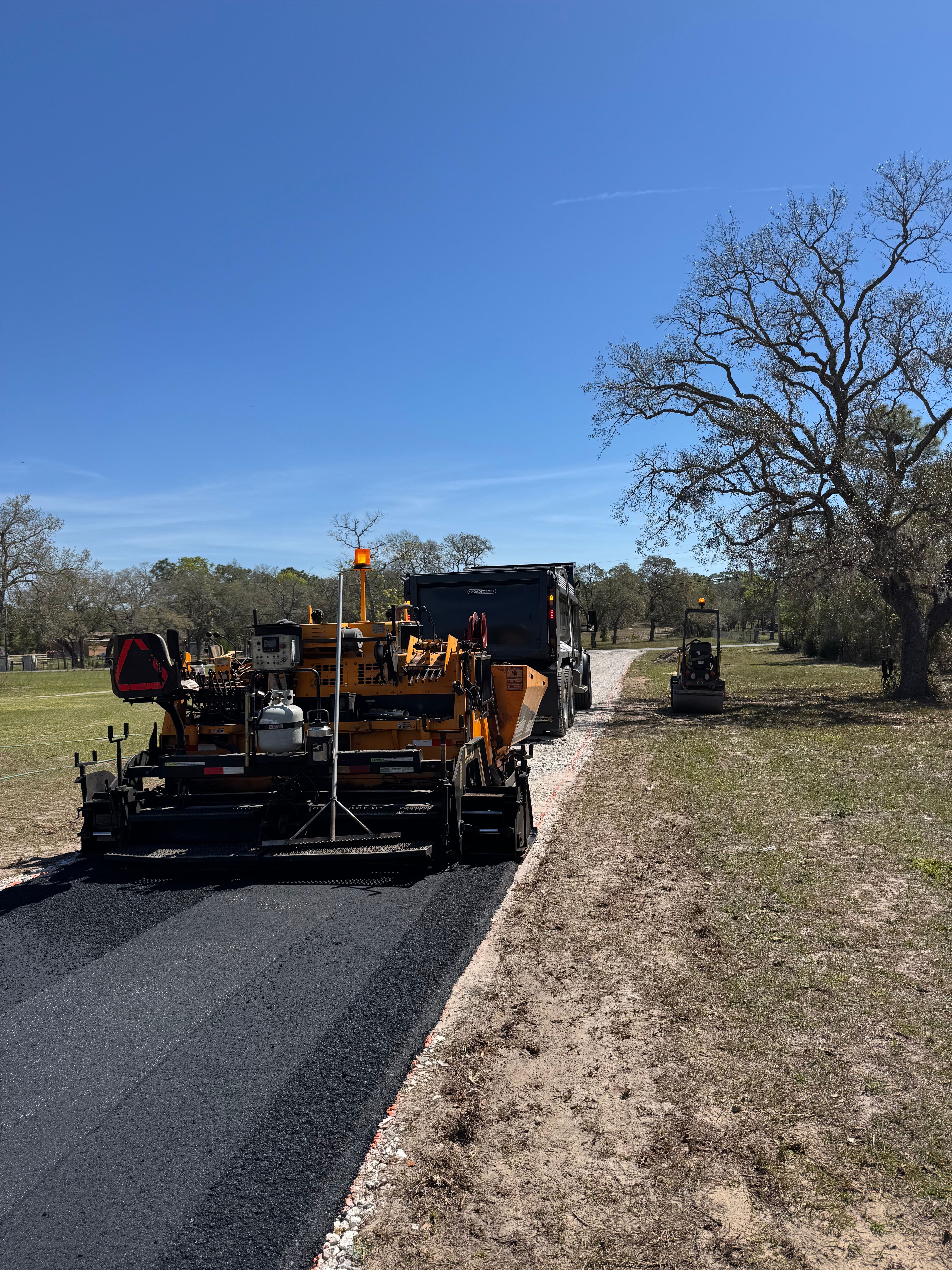 Paver placing asphalt on a long rural driveway