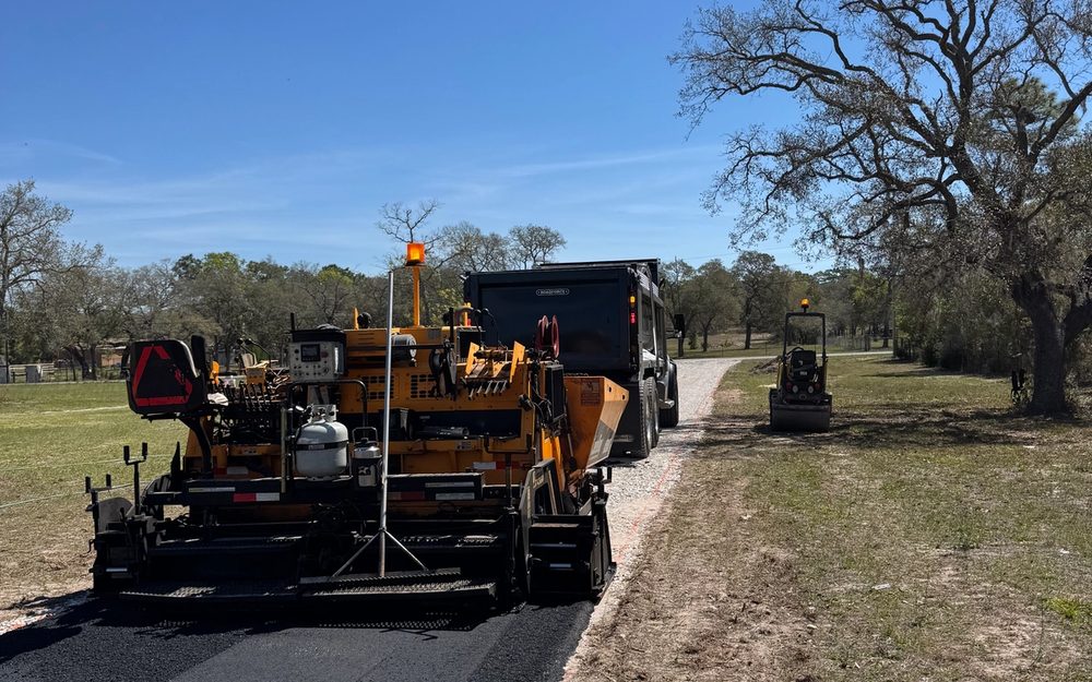 Paver placing asphalt on a long rural driveway
