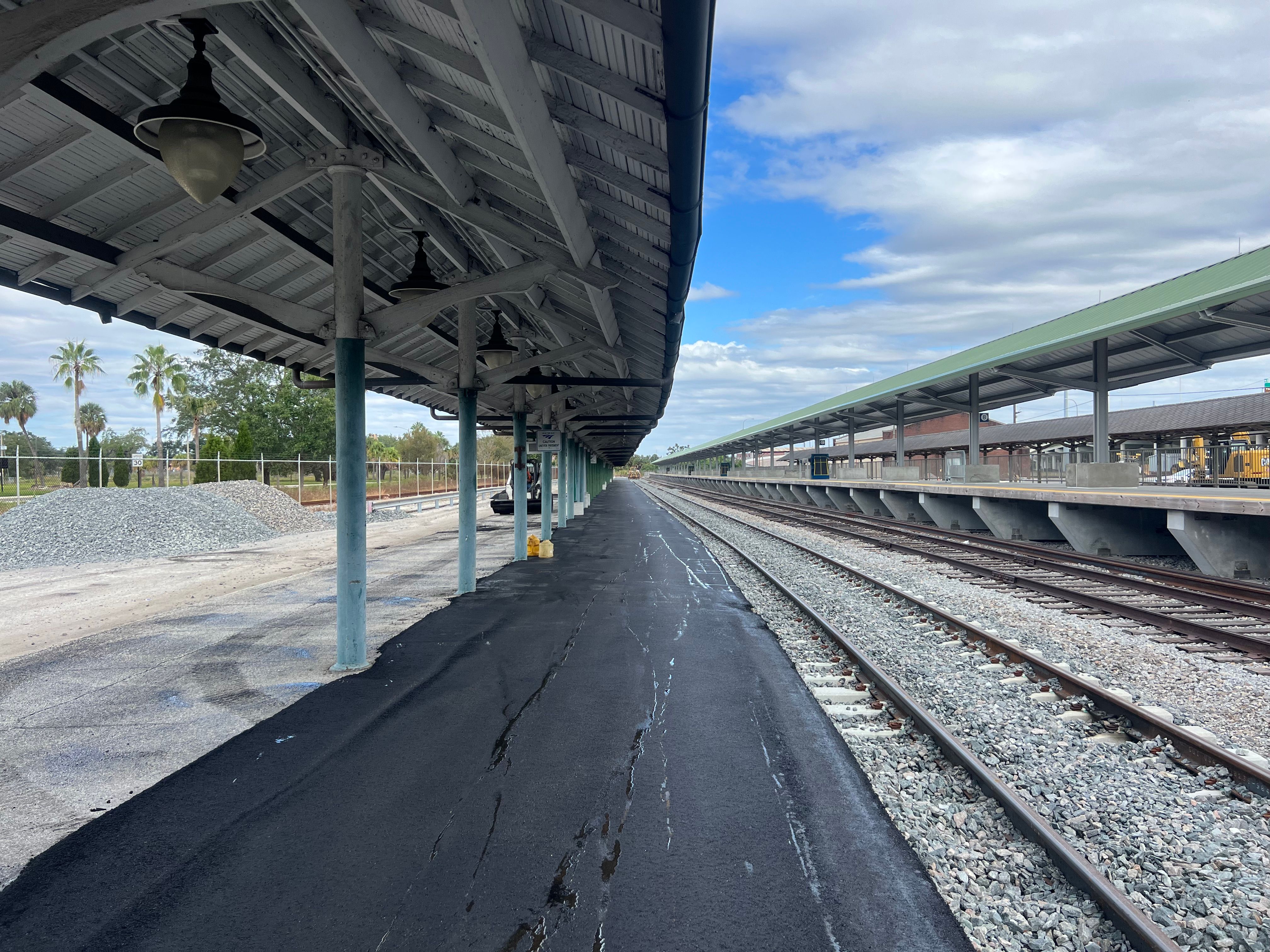 Asphalt paving equipment working beside a covered platform
