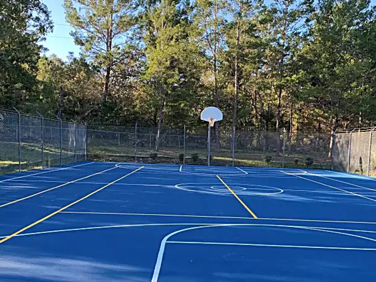 Resurfaced blue basketball court with fresh white and yellow game lines