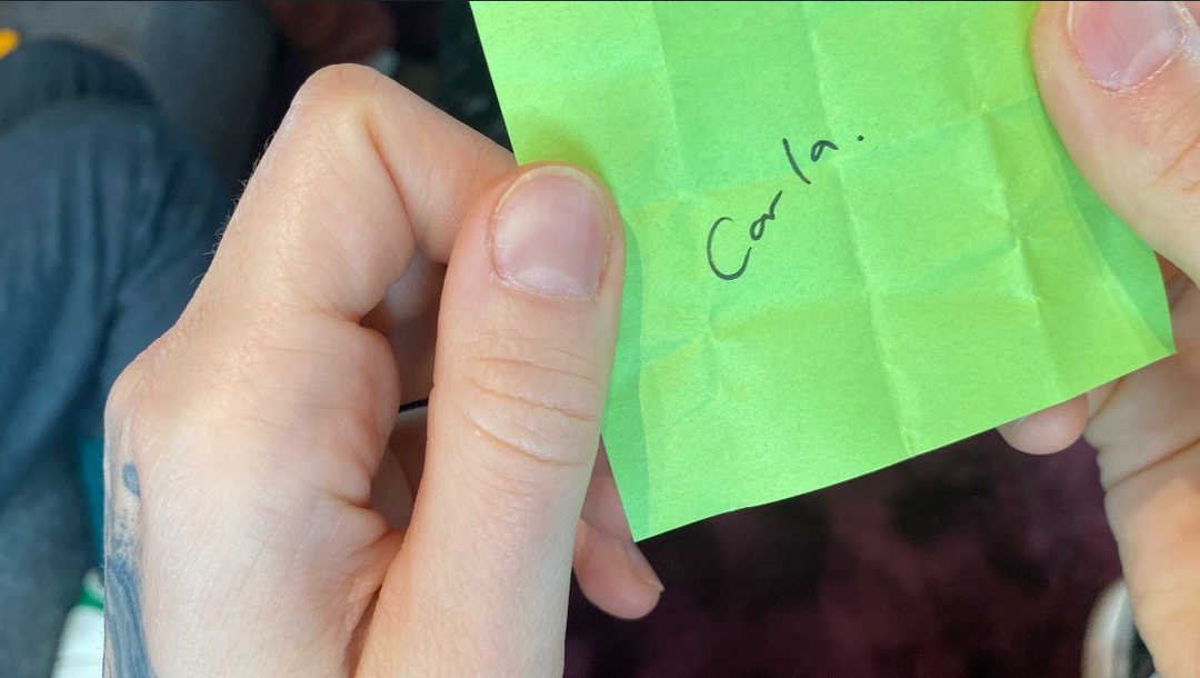 Two hands holding a post-it reading Carla.