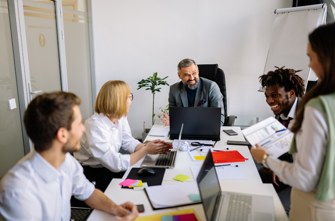 A diverse team smiling and collaborating in a workplace meeting