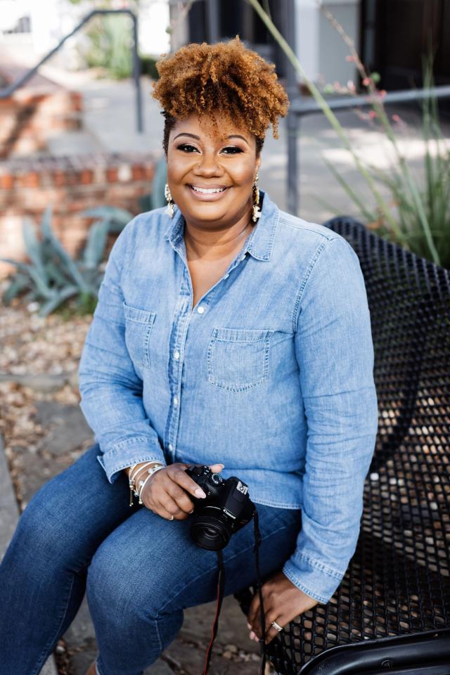 Julie Andrea seated outdoors with her camera, relaxed and smiling