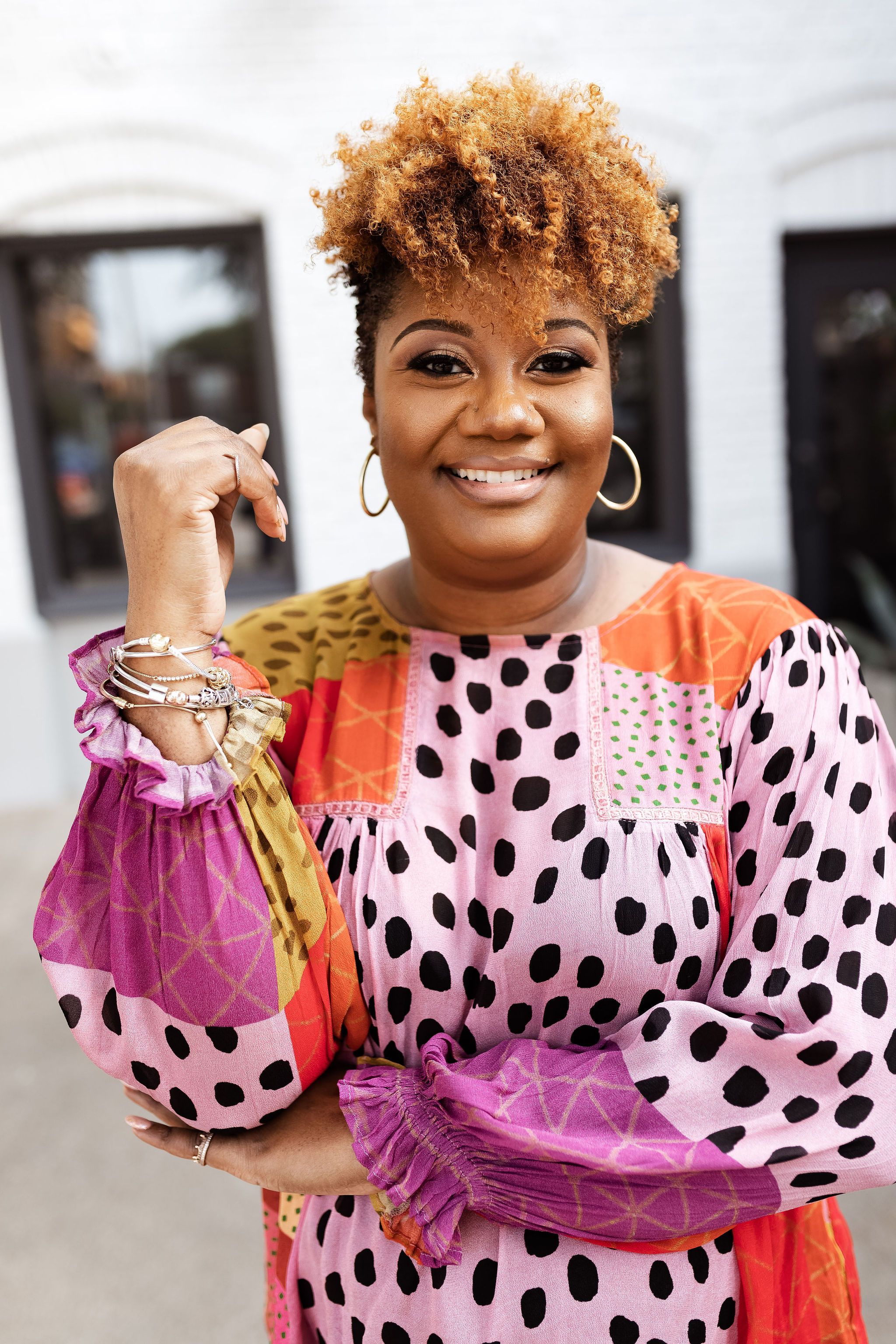 Julie Andrea smiling and holding a colorful patterned bag outside a storefront