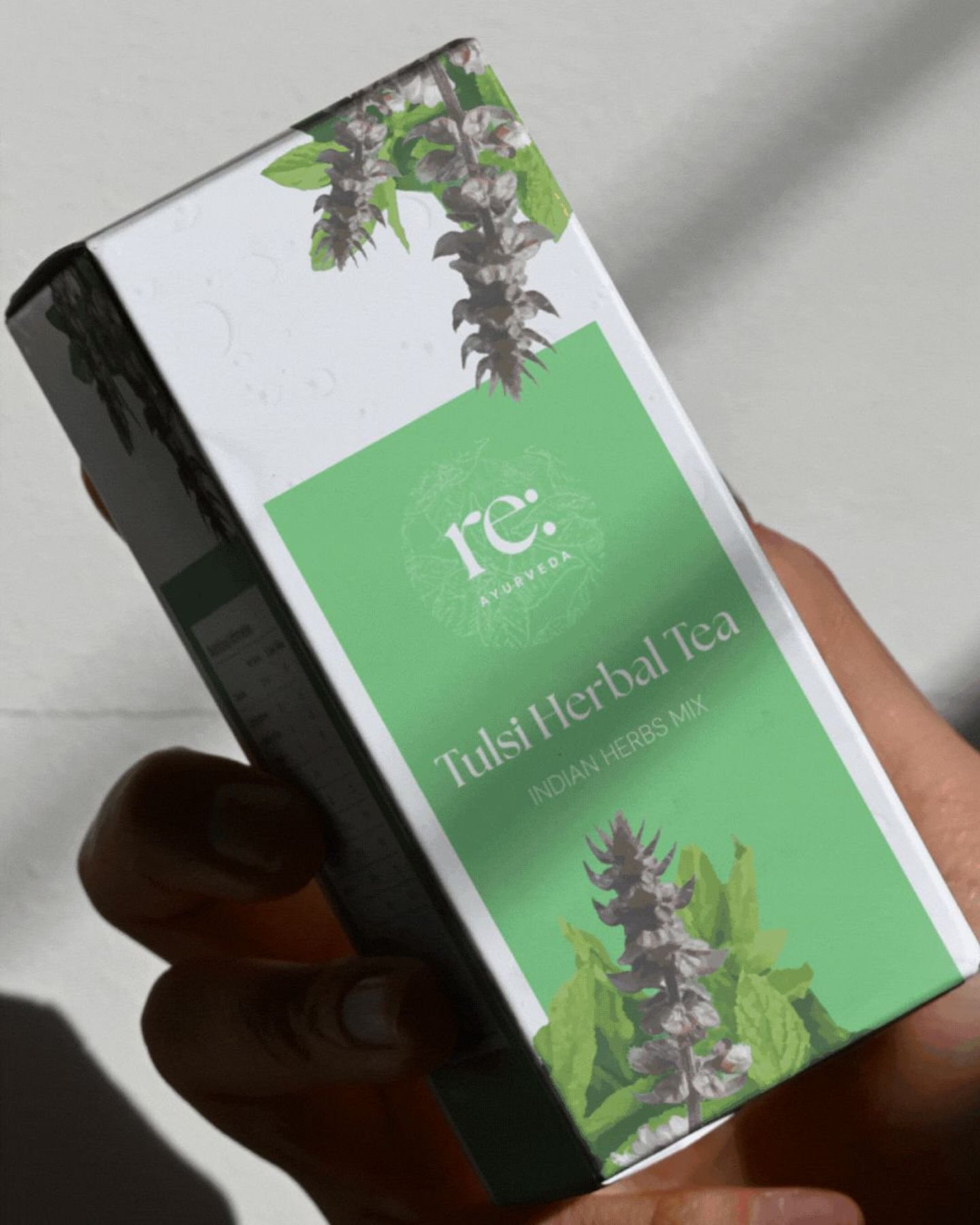 A hand holding the Tulsi Herbal Tea box