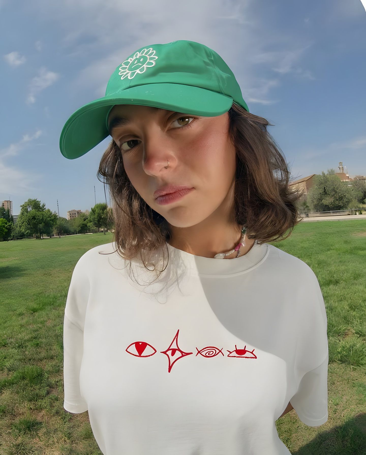 Model in a green cap and white Ariiston tee on grass