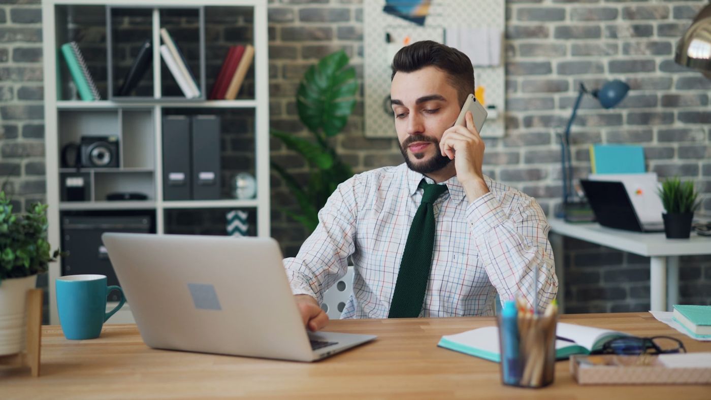 Un homme en chemise au téléphone à son bureau