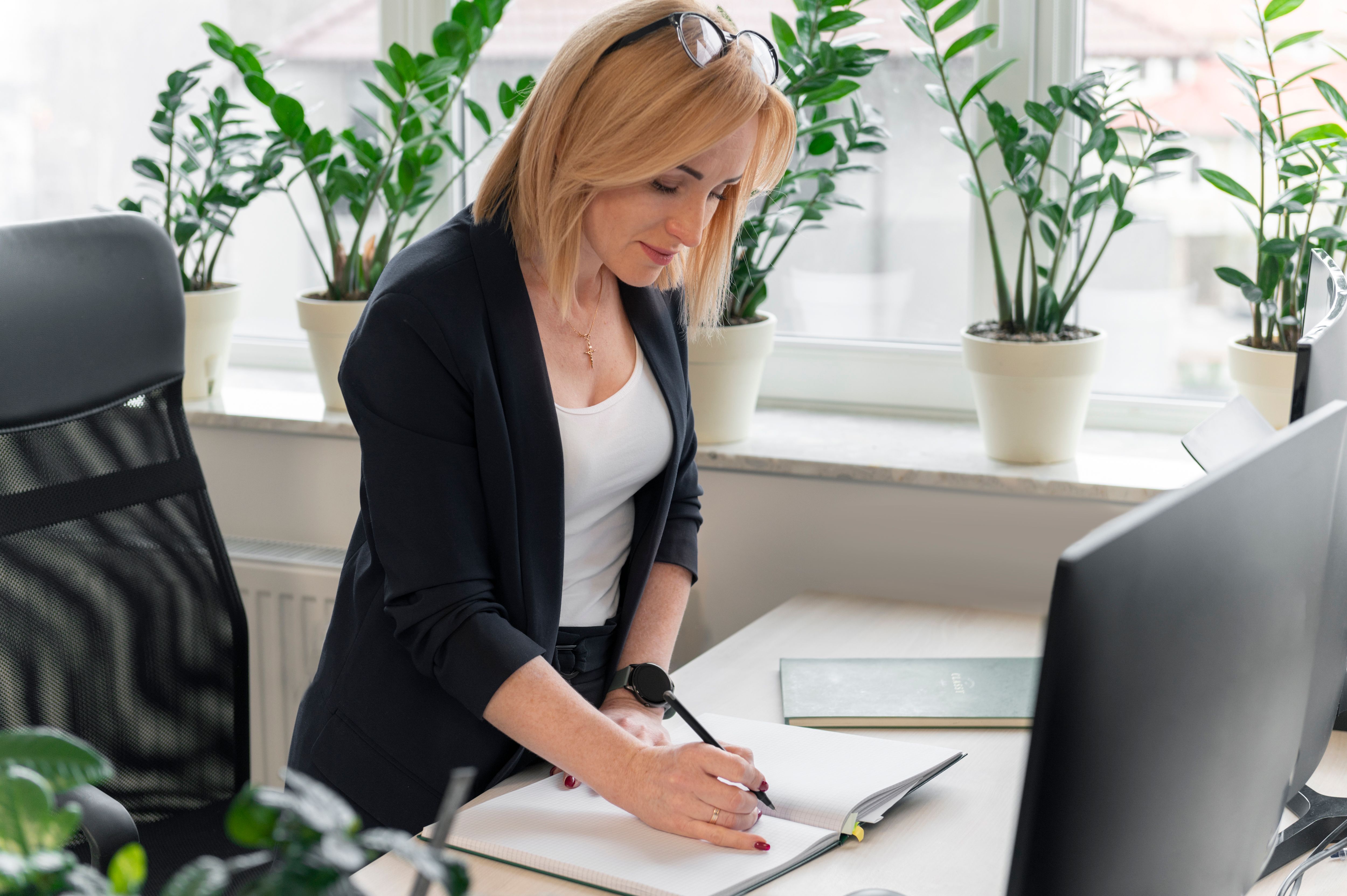 Une femme debout prend des notes à son bureau