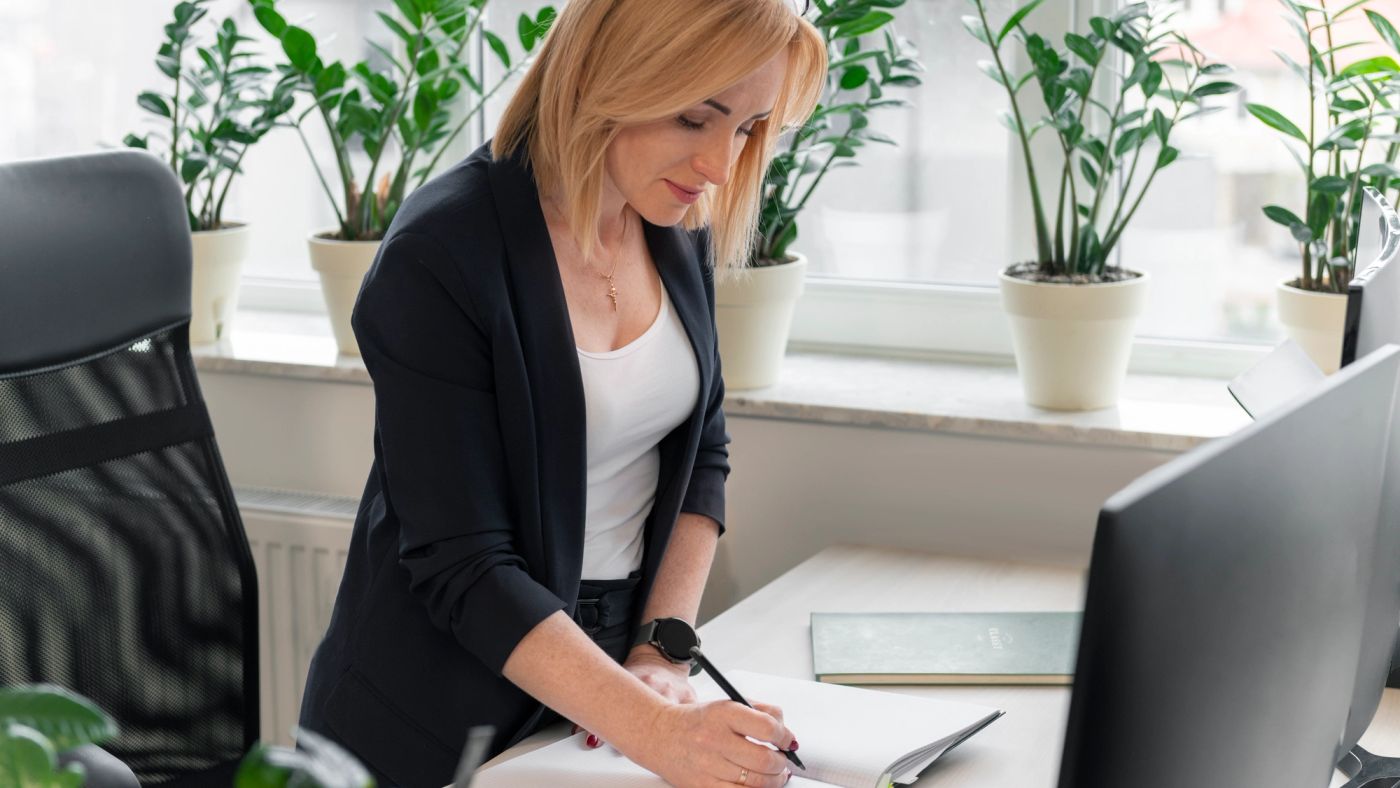 Une femme debout prend des notes à son bureau