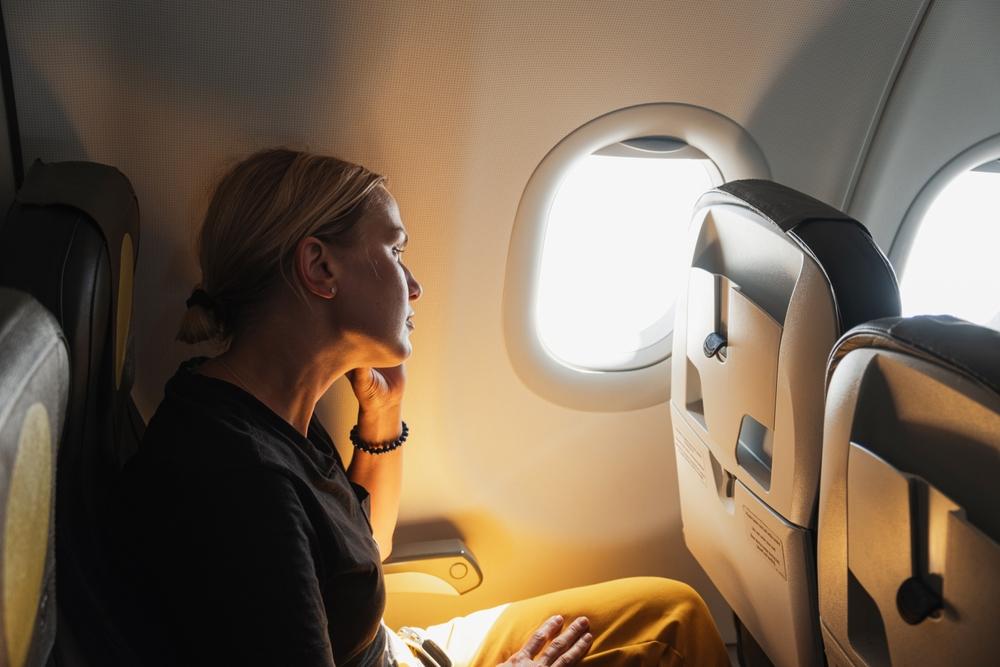 A woman wearing yellow trousers travelling on a flight for business ruminates A woman wearing yellow trousers travelling on a flight for business ruminates