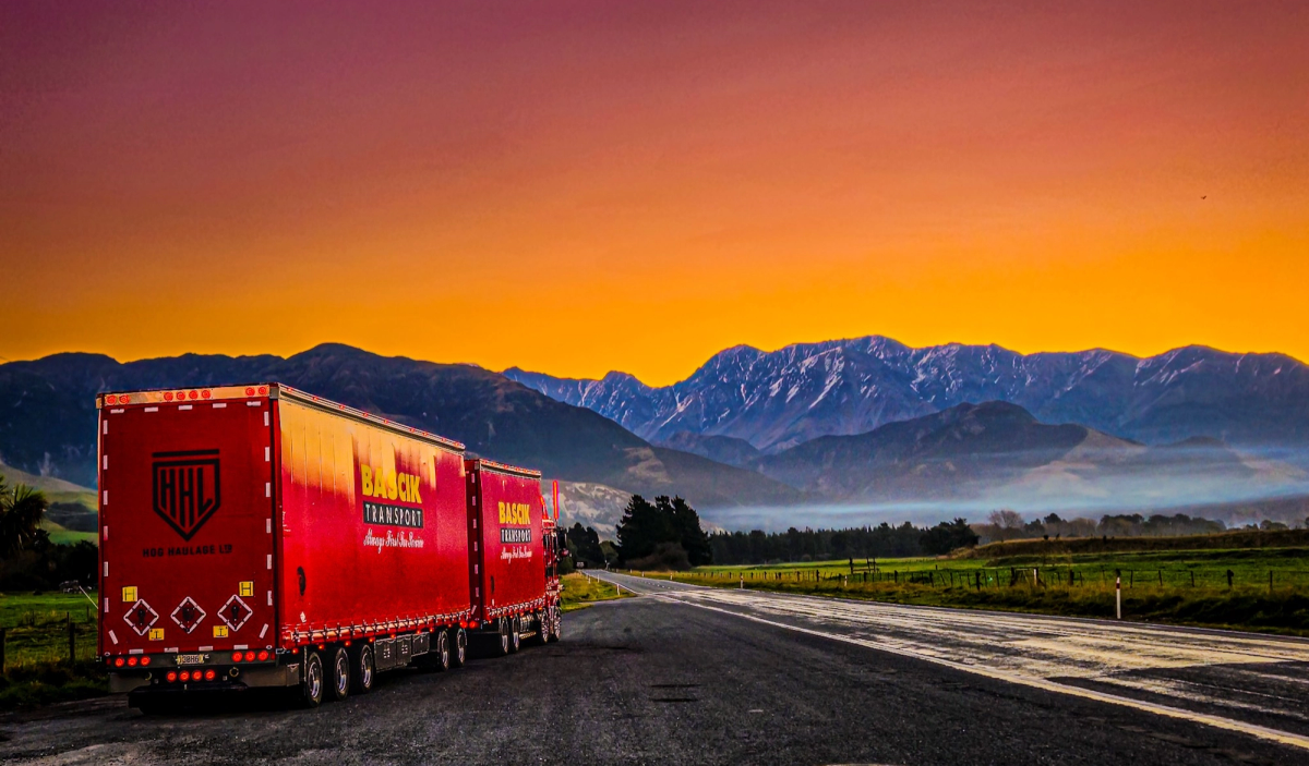 Bascik Transport truck driving through New Zealand mountainous landscape at sunrise