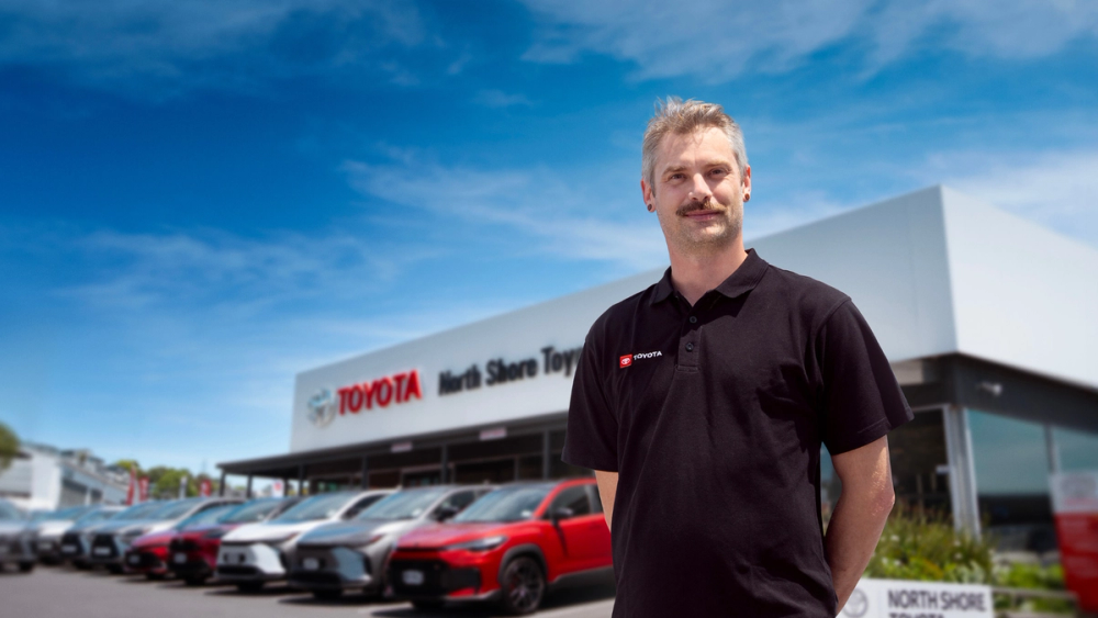 A photo of a HSE and Compliance Officer standing proudly in front of Toyota dealership