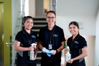Three workers at Jani King smiling for photo holding cleaning products