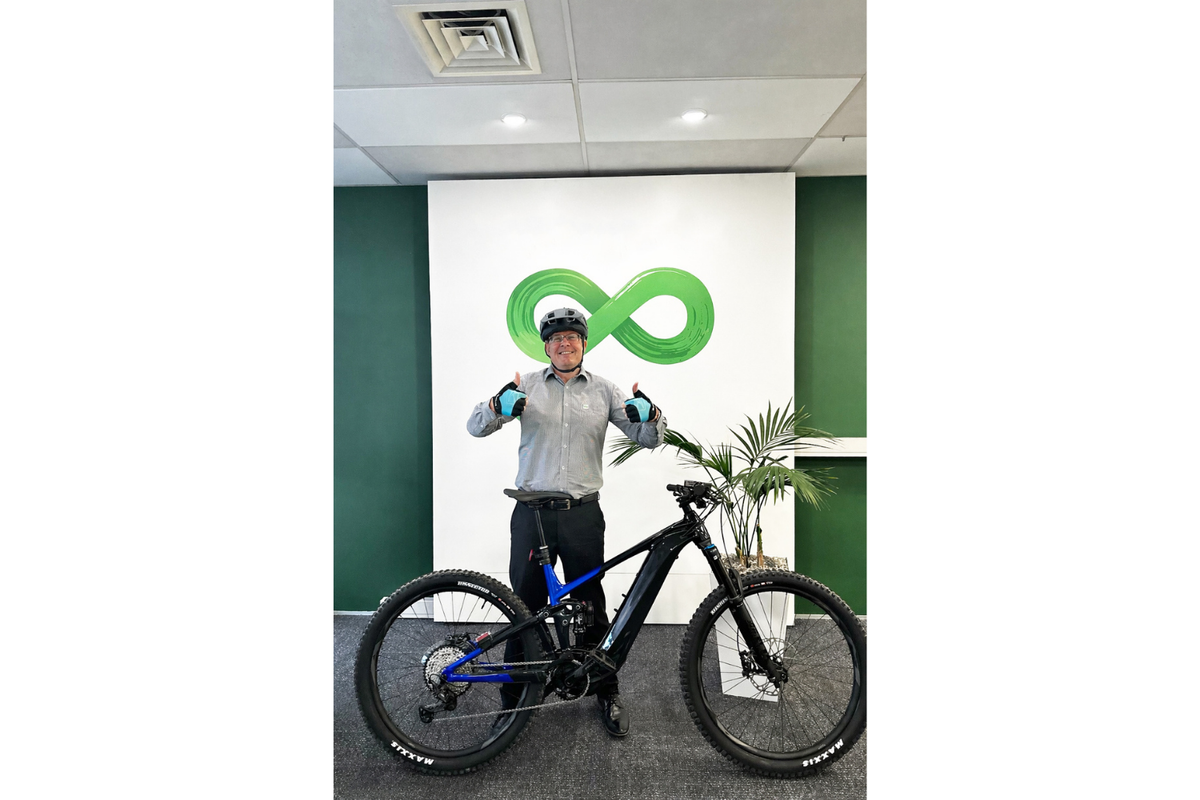 Photo of man giving the thumbs up with his bicycle in front of the co op bank logo