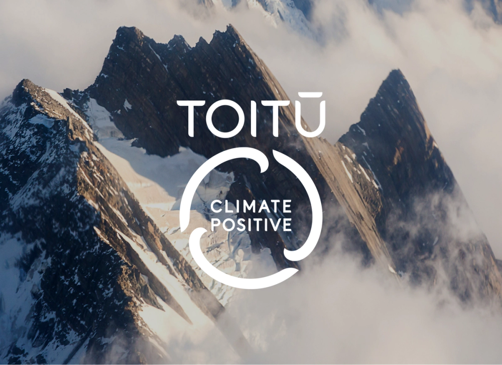 Toitu Carbon Positive Mark over mountain backdrop Toitu Carbon Positive Mark over mountain backdrop