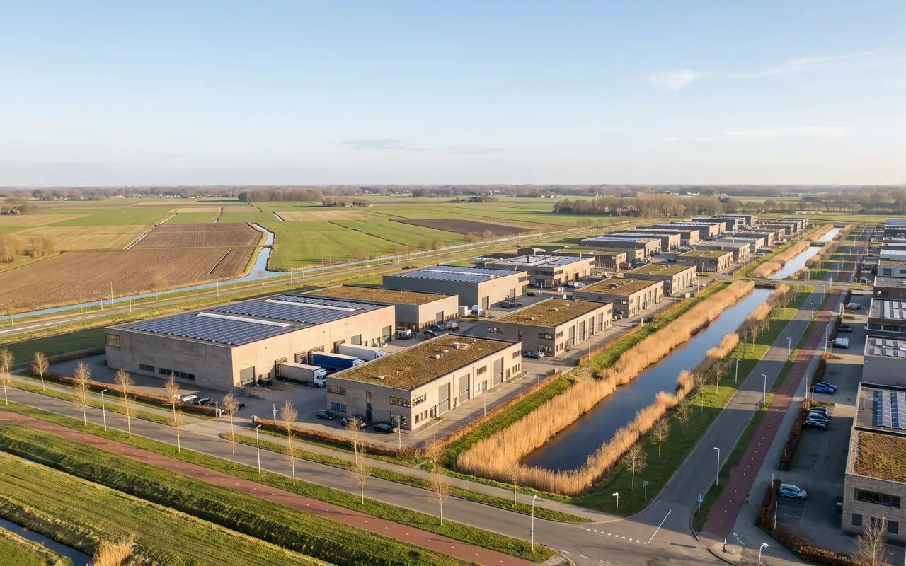 Luchtfoto van een bedrijventerrein met zonnedaken, groene daken en water