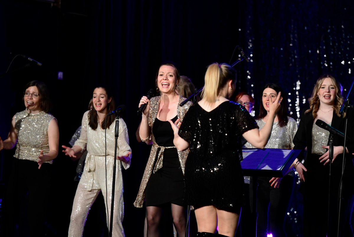 Frauen auf der Bühne singen vor Mikrofonen