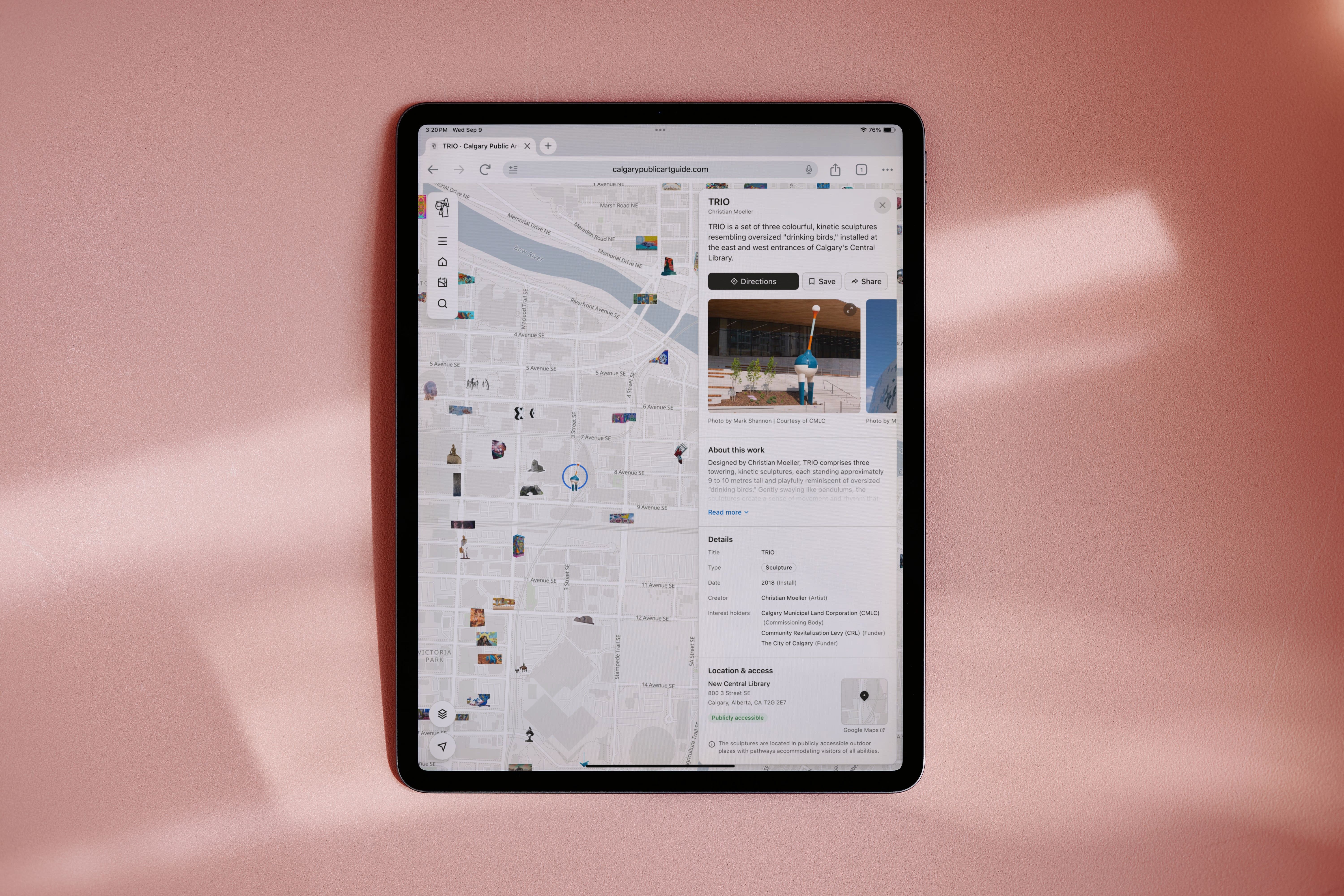The Calgary Public Art Guide on a tablet lying on a pink surface, showing the artwork map beside an artwork's detail panel.