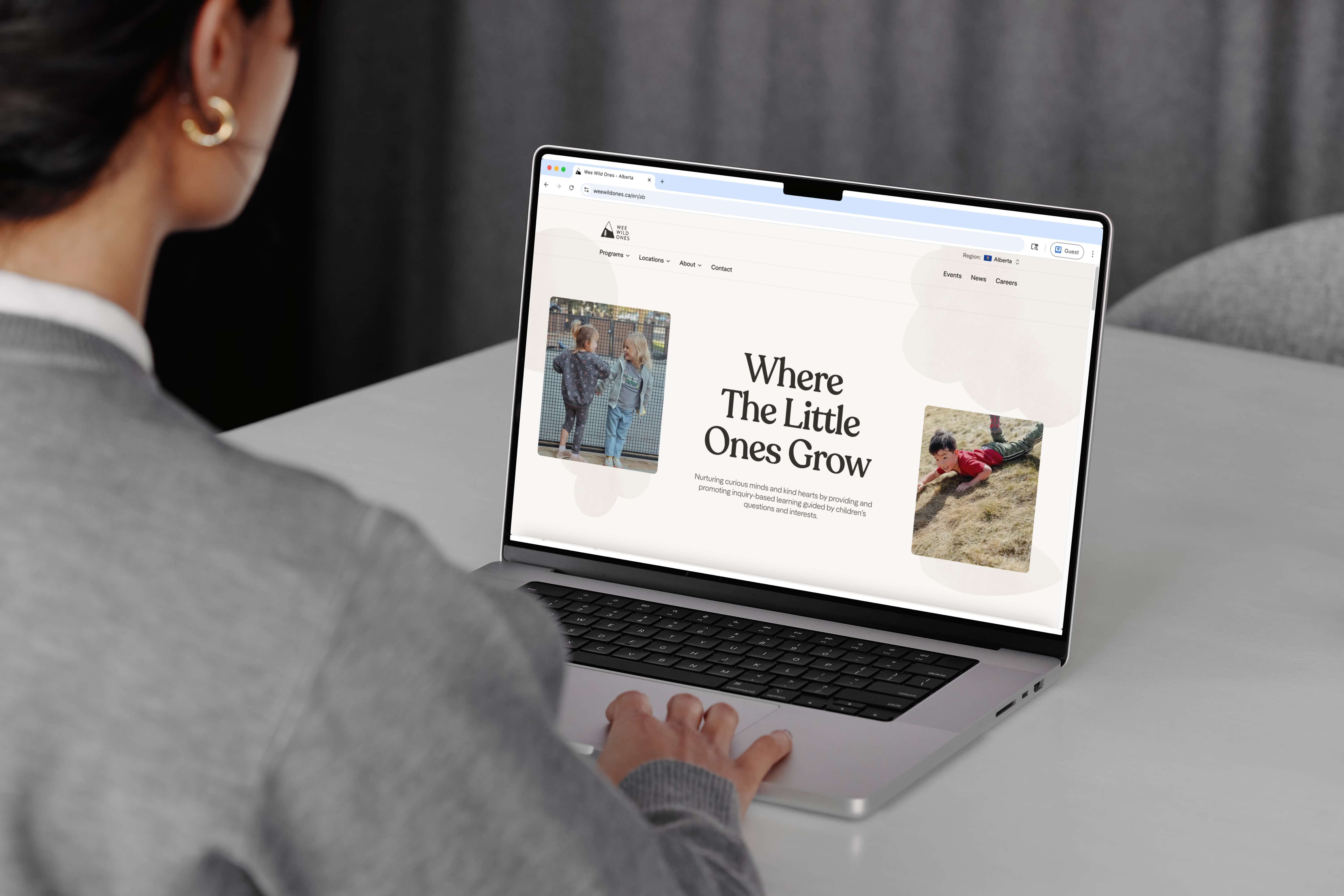 A person at a laptop viewing the Wee Wild Ones homepage, headed Where The Little Ones Grow.