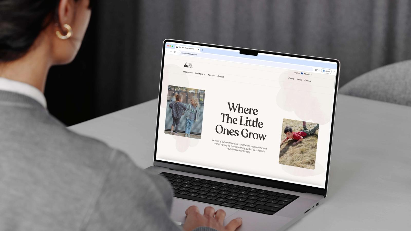 A person at a laptop viewing the Wee Wild Ones homepage, headed Where The Little Ones Grow.