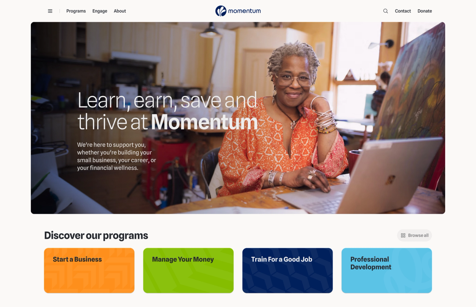 Momentum nonprofit homepage with navigation, a smiling woman at a laptop hero headlined 'Learn, earn, save and thrive at Momentum,' and four colored program tiles.