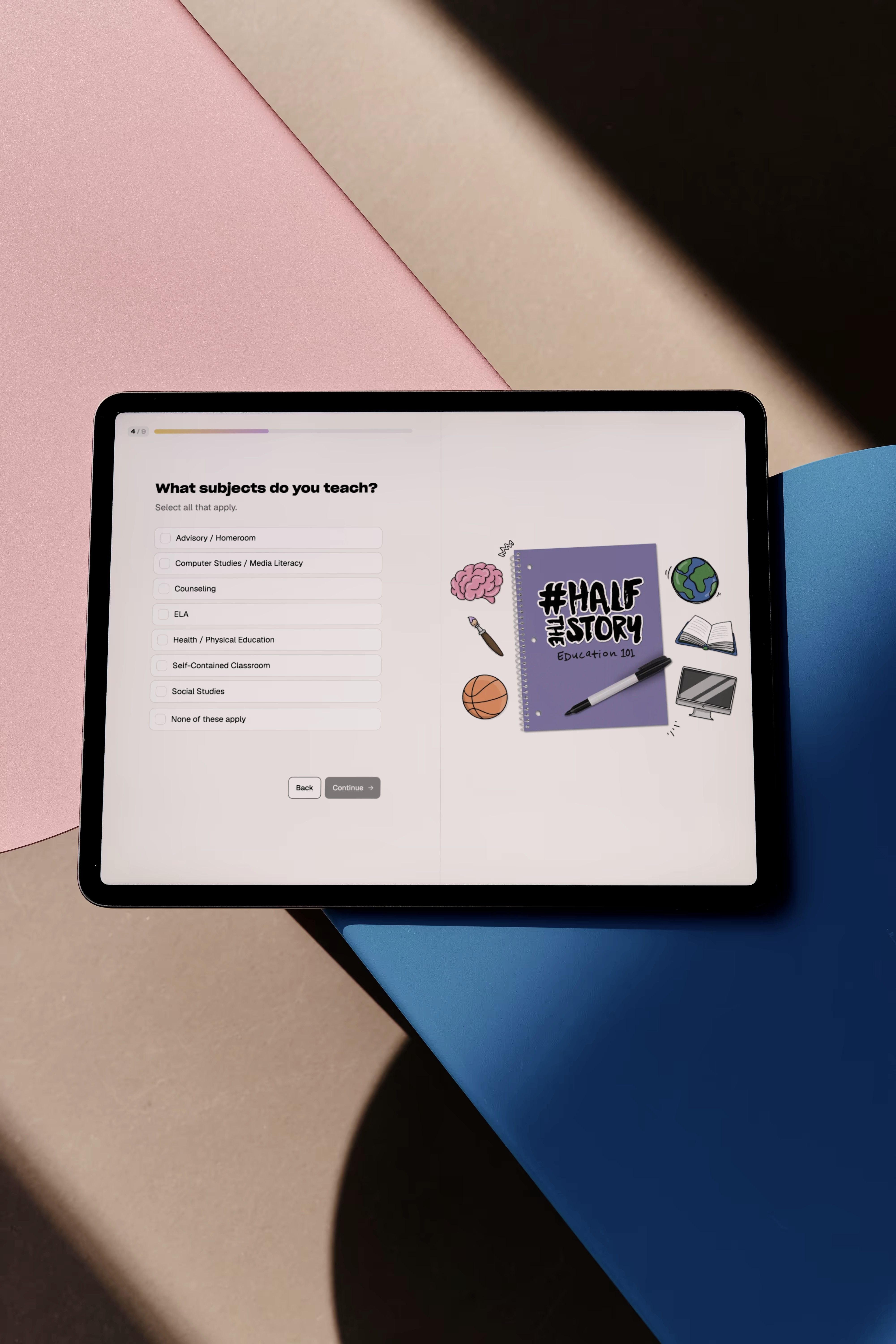 The #HalfTheStory onboarding step What subjects do you teach? on a tablet lying across pink and blue paper.