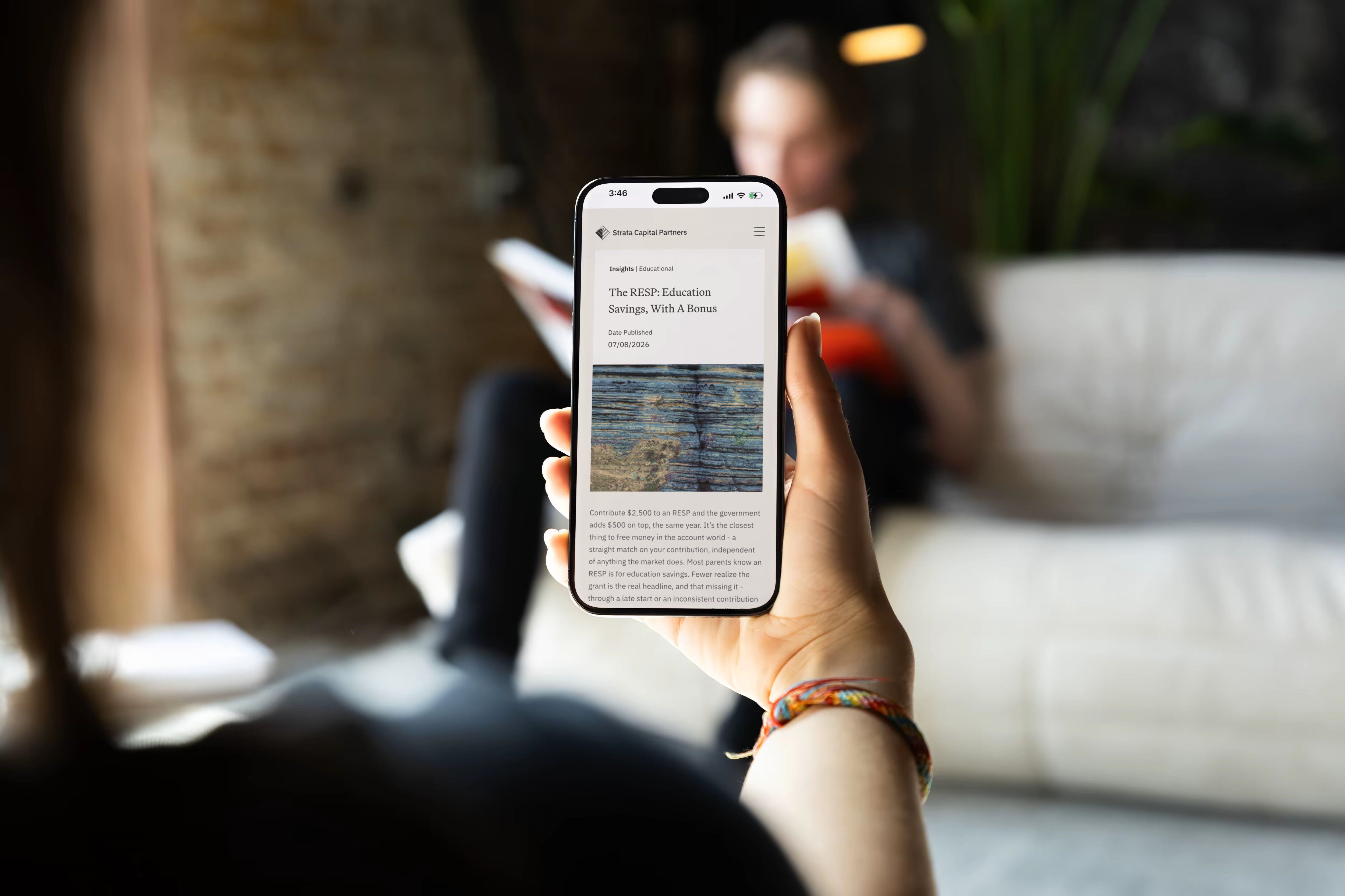 A hand holding a phone that shows a Strata Capital Partners insights article about RESP education savings.