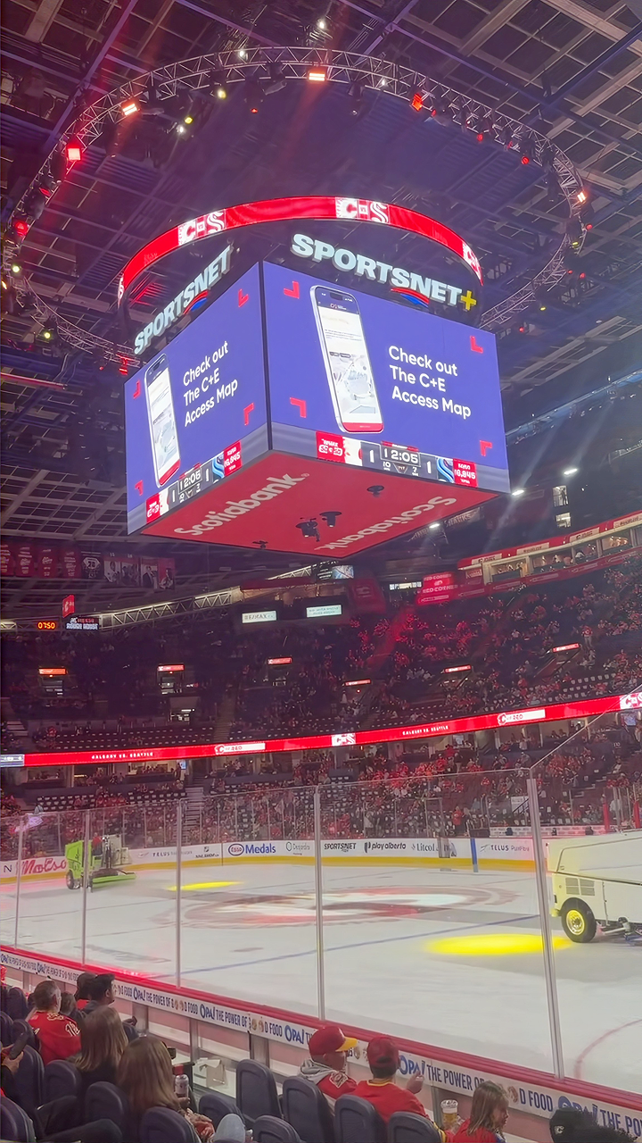 The Scotiabank Saddledome jumbotron showing a Check out the C+E Access Map promo above the ice before a Calgary Flames pre-season game.
