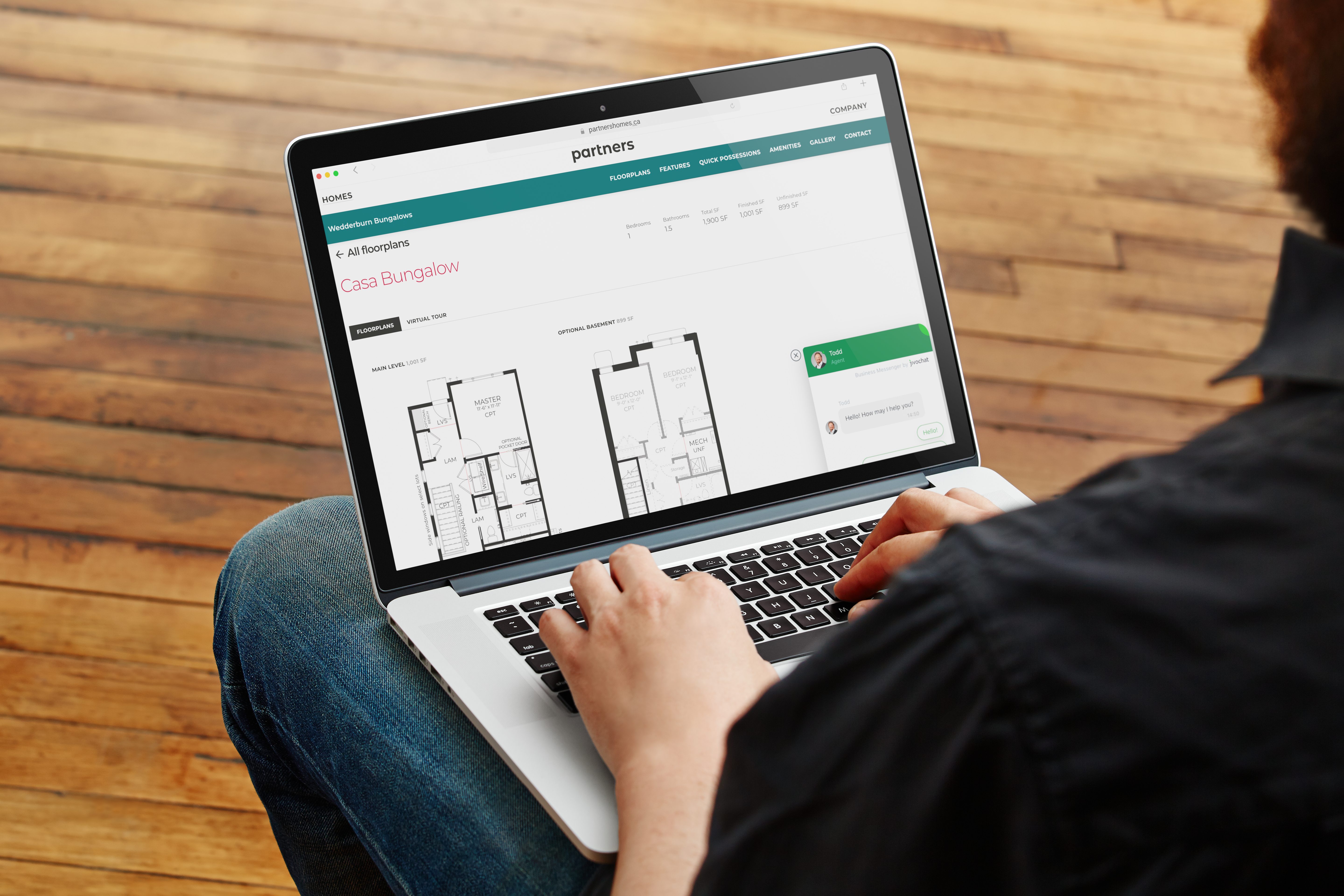 A person using a laptop that shows a bungalow floor plan page on the Partners Development Group website.