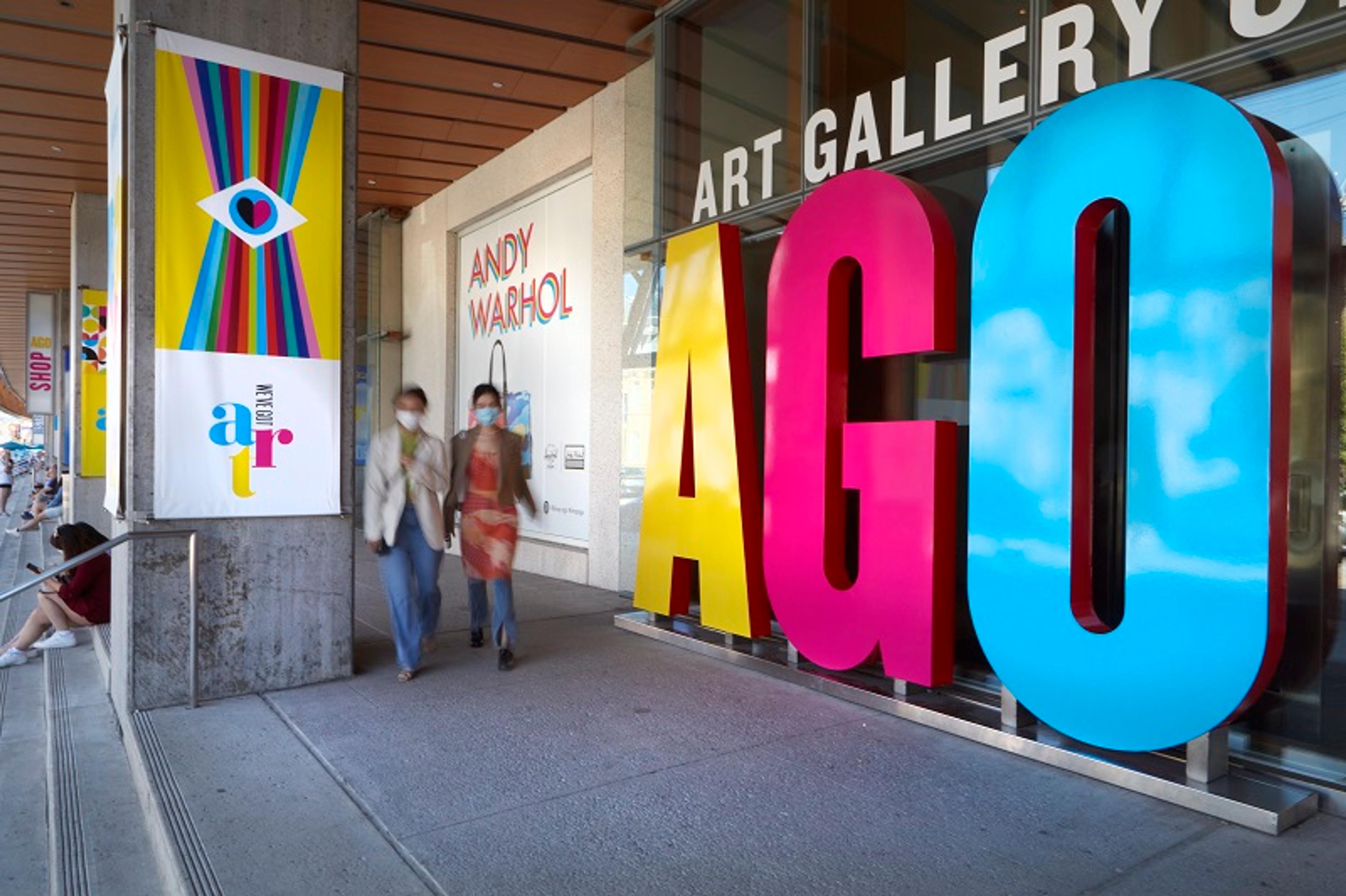 Two people walk by the entrance to the AGO