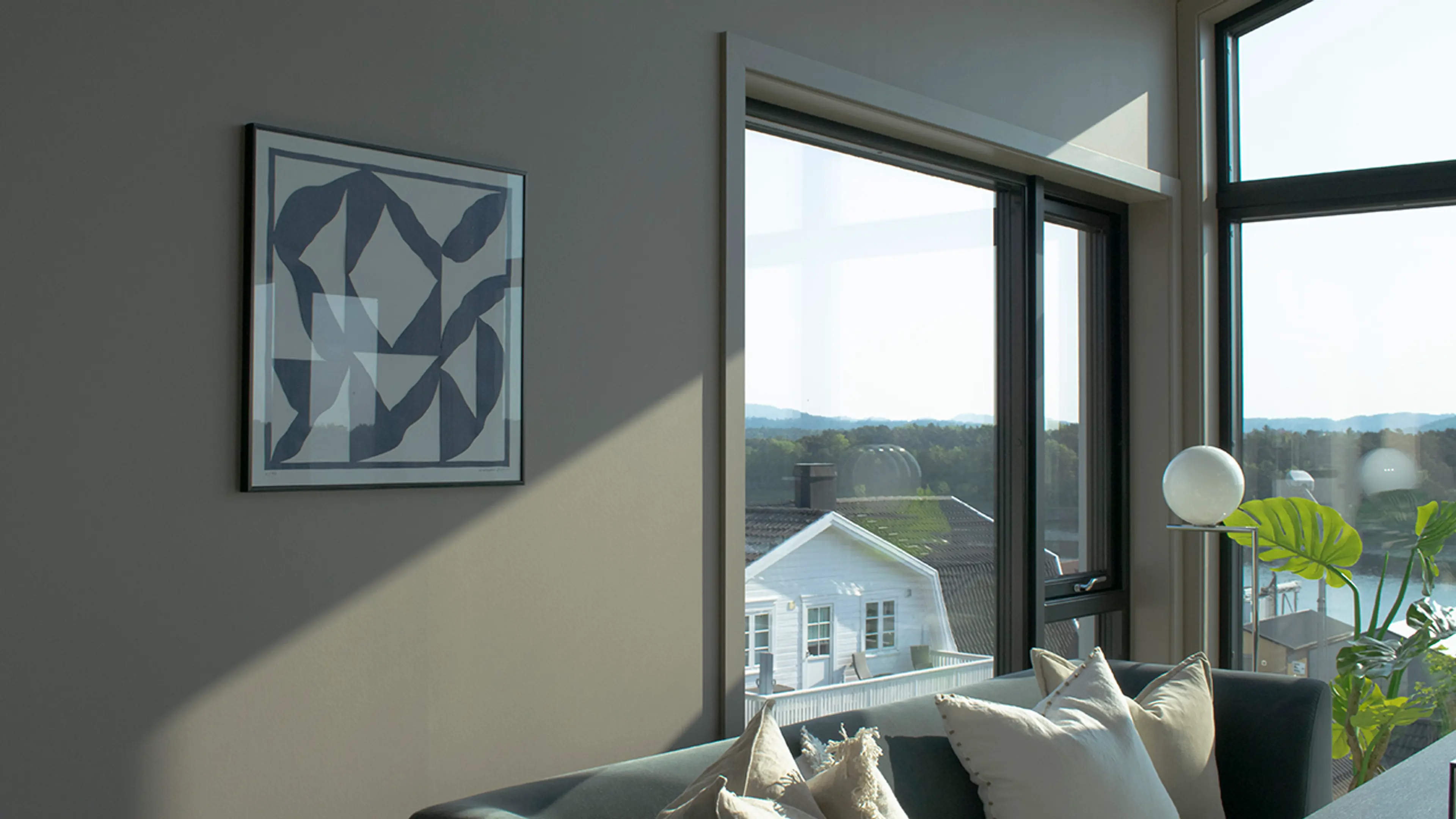Gråbeige stue i moderne hus med glatte lister rundt vinduene.