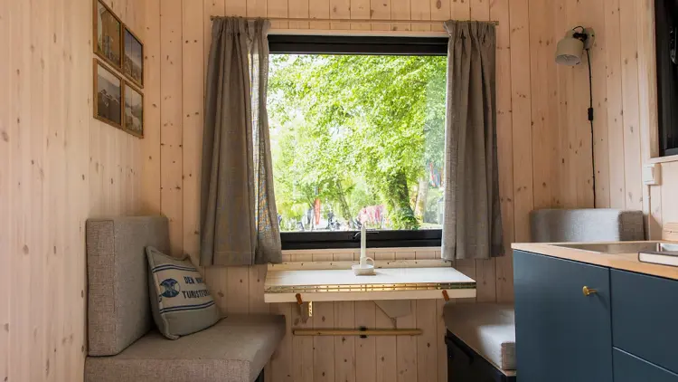 Minihytte med sittegruppe, utfellbart bord og blått kjøkken.