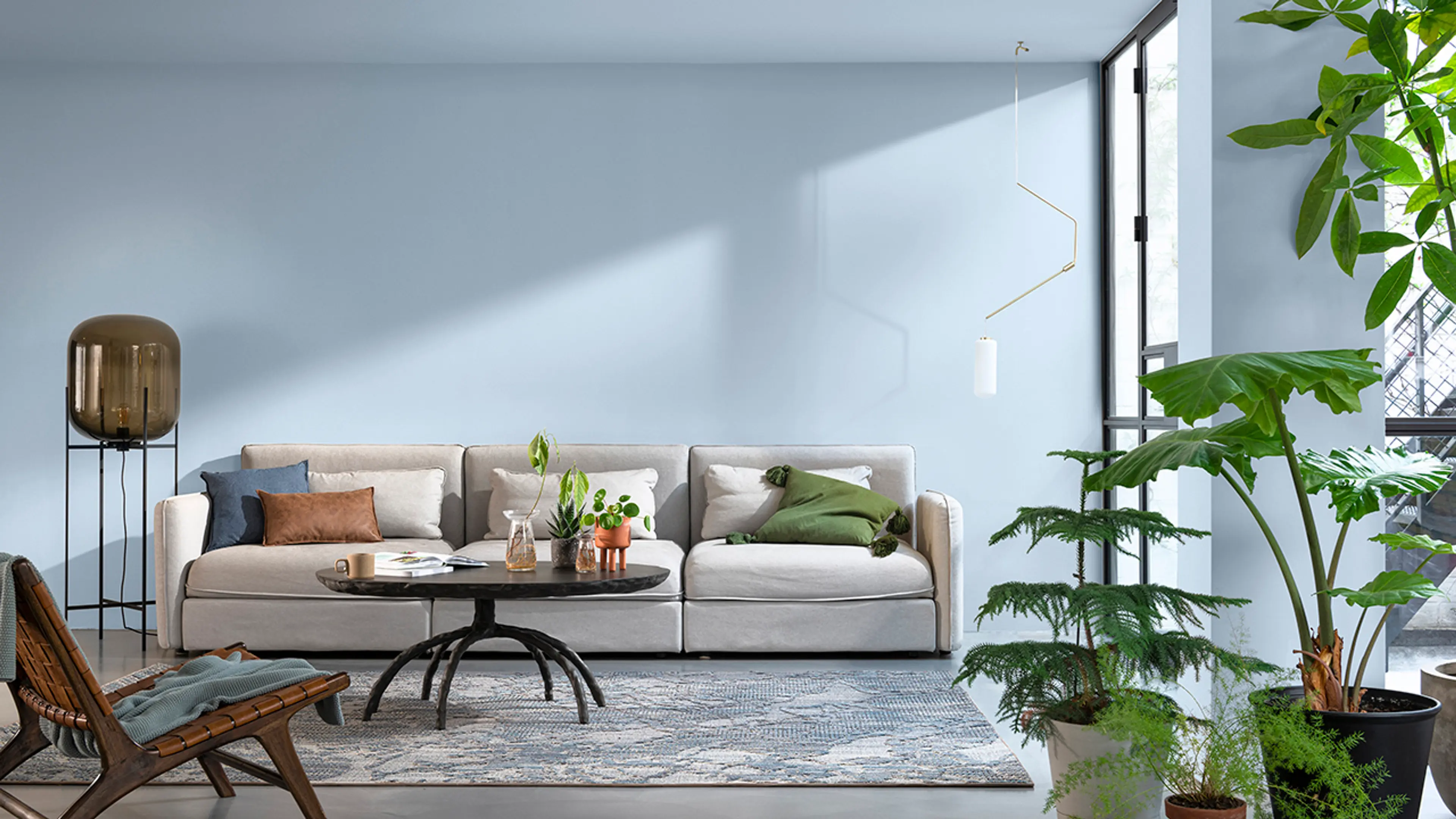 Stue med sofa og grønne planter hvor både vegger og tak er malt i samme lyseblå farge.