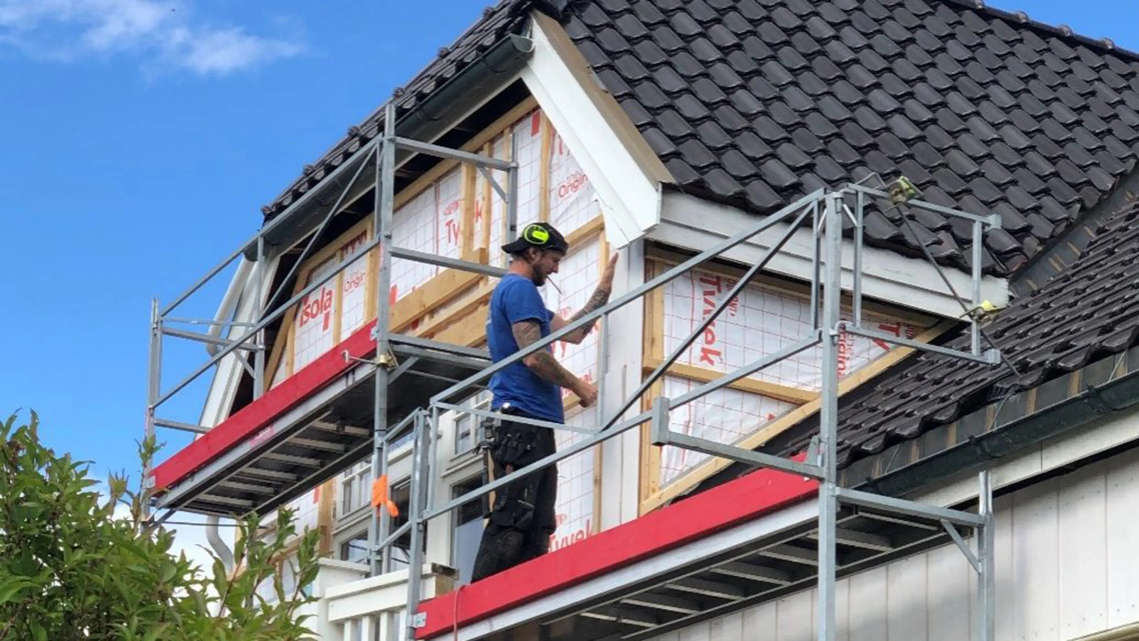 Håndverker som monterer vindsperre på hus.