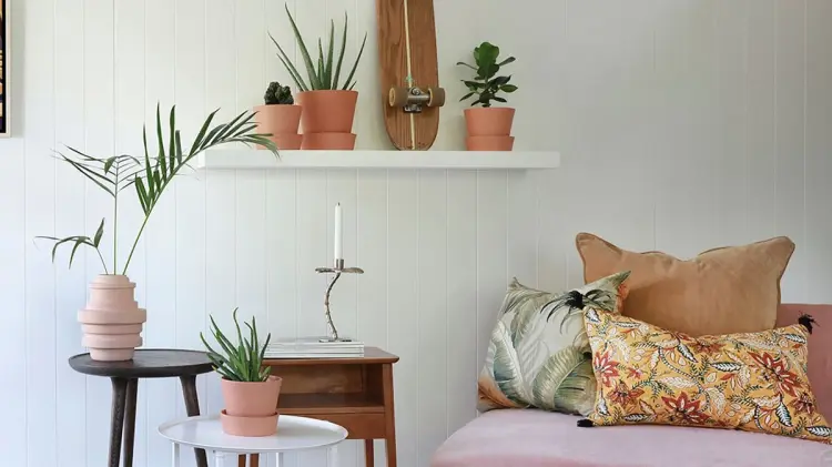 Hvitt huntonit veggpanel i tre, med planter, bord og sitteplass. 