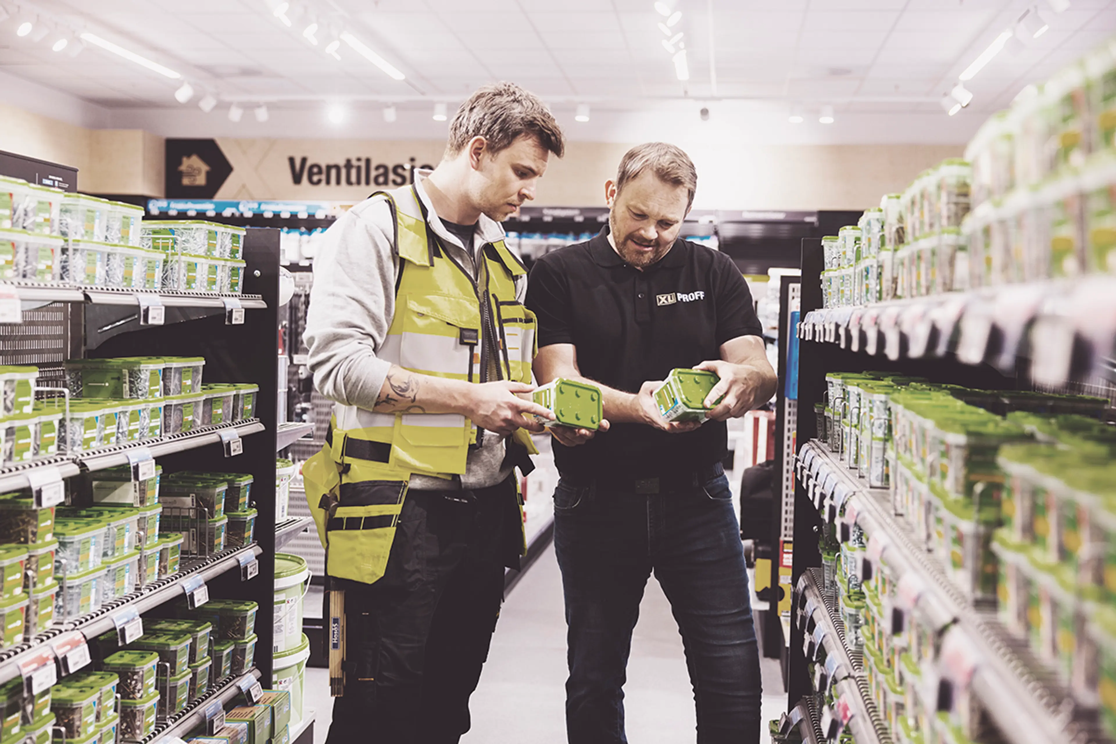 to menn ser på ulike bokser med festemidler i en XL-BYGG butikk