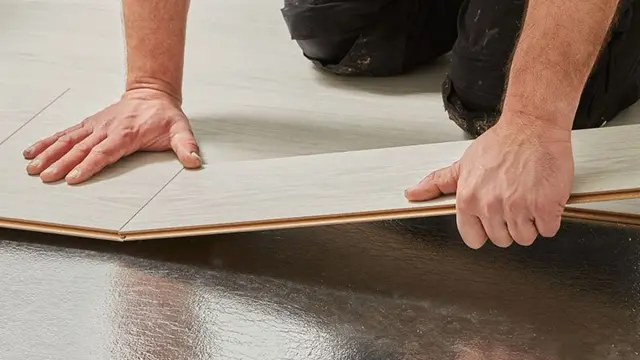 Nærbilde av hendene til en håndverker som legger gulv etter avretting.