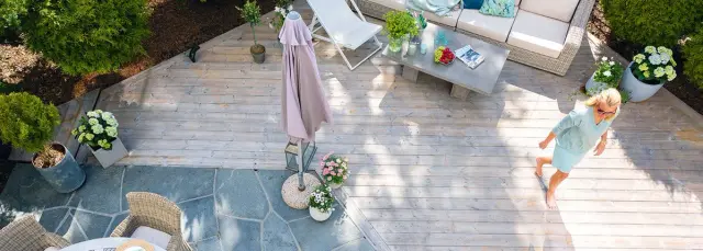 sommerlig kledd kvinne går barbeint over en terrasse